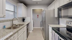 A modern kitchen with white cabinets, a granite countertop, stainless steel appliances, and a black oven. - Modern Comfort Lux Stay | Near DFW Airport (Euless)