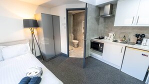 A hotel room with a bed, a desk, a kitchenette, and a bathroom. - Captivating 1-Bed studio in Birmingham (Birmingham)