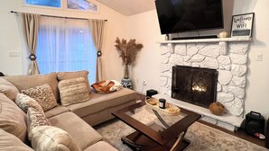 Un salon moderne avec un canapé d’angle, une cheminée, un téléviseur à écran plat et une table basse.