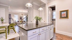 A modern kitchen with a central island, white cabinetry, and pendant lighting.