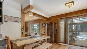 A wooden interior with a dining table, benches, a clock, and a view of the outdoors. - The Bear Den  (Florissant)
