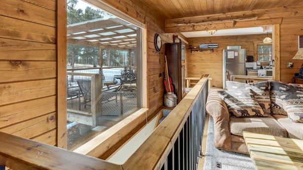 A cabin with a wooden interior, a dining area, and a kitchen. - The Bear Den  (Florissant)