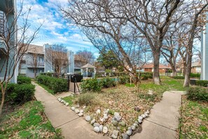 A residential area with houses, a pathway, and a small garden with rocks and plants.