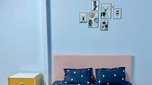 A bedroom with a bed, a nightstand, and an air conditioner on the wall. - ĐOAN GIA (Dong Xoai)