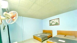 A room with two beds, a standing fan, a wall-mounted light, and a floral painting. - ĐOAN GIA (Dong Xoai)