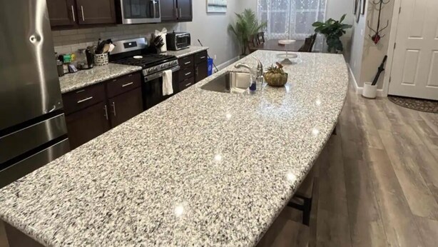 Una cocina moderna con encimeras de granito, electrodomésticos de acero inoxidable y armarios de madera oscura.