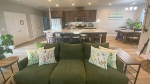 Una sala de estar con un sofá verde, una mesa de centro y un comedor con una mesa y sillas.
