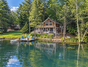 A house with a dock, surrounded by trees and a body of water.