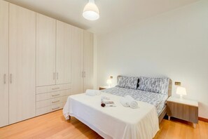 A bedroom with a bed, nightstands, a wardrobe, and a ceiling light.