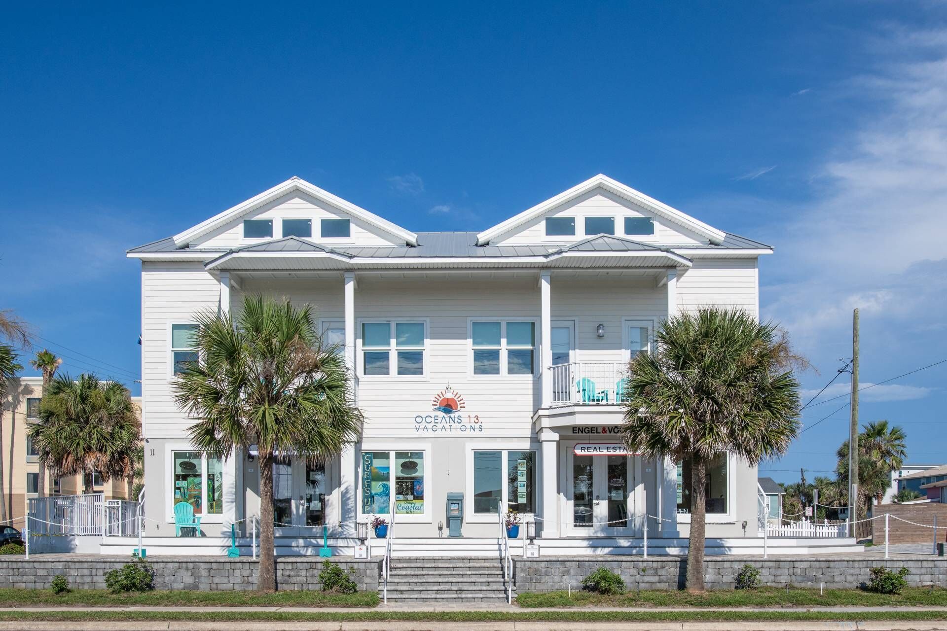 A white two-story building with a sign for 'OCEANS 13 VACCATIONS'.