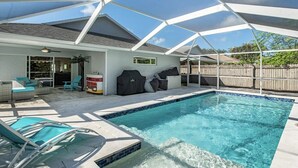 Un jardin avec une piscine, un espace salon extérieur et un barbecue.