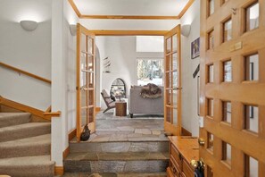 A staircase leading to a living area with a fireplace, a sofa, and a view of trees outside. - 122 West Meadow Drive (Vail)