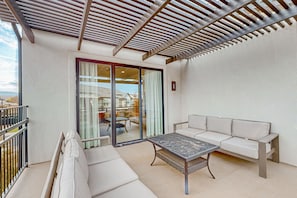 A balcony with a white sofa, a small table, and a pergola overhead. - Enchanting townhome with pool, hot tub, fire pit, games, & great balcony views (Santa Clara)