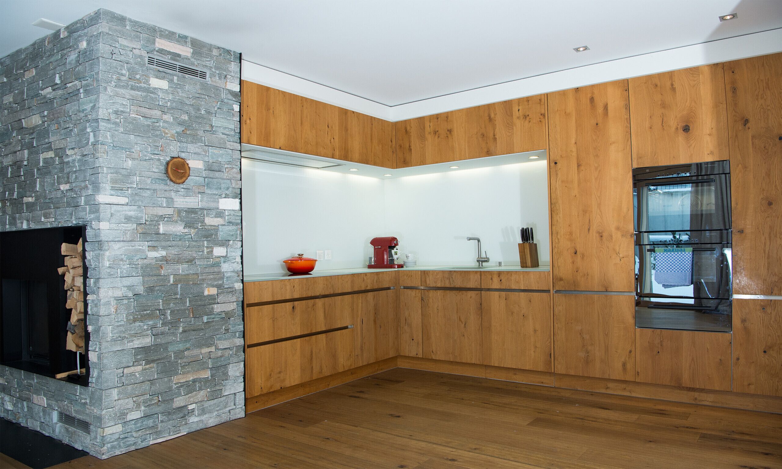 Een moderne keuken met een stenen muur, houten kastjes en een inbouwoven.