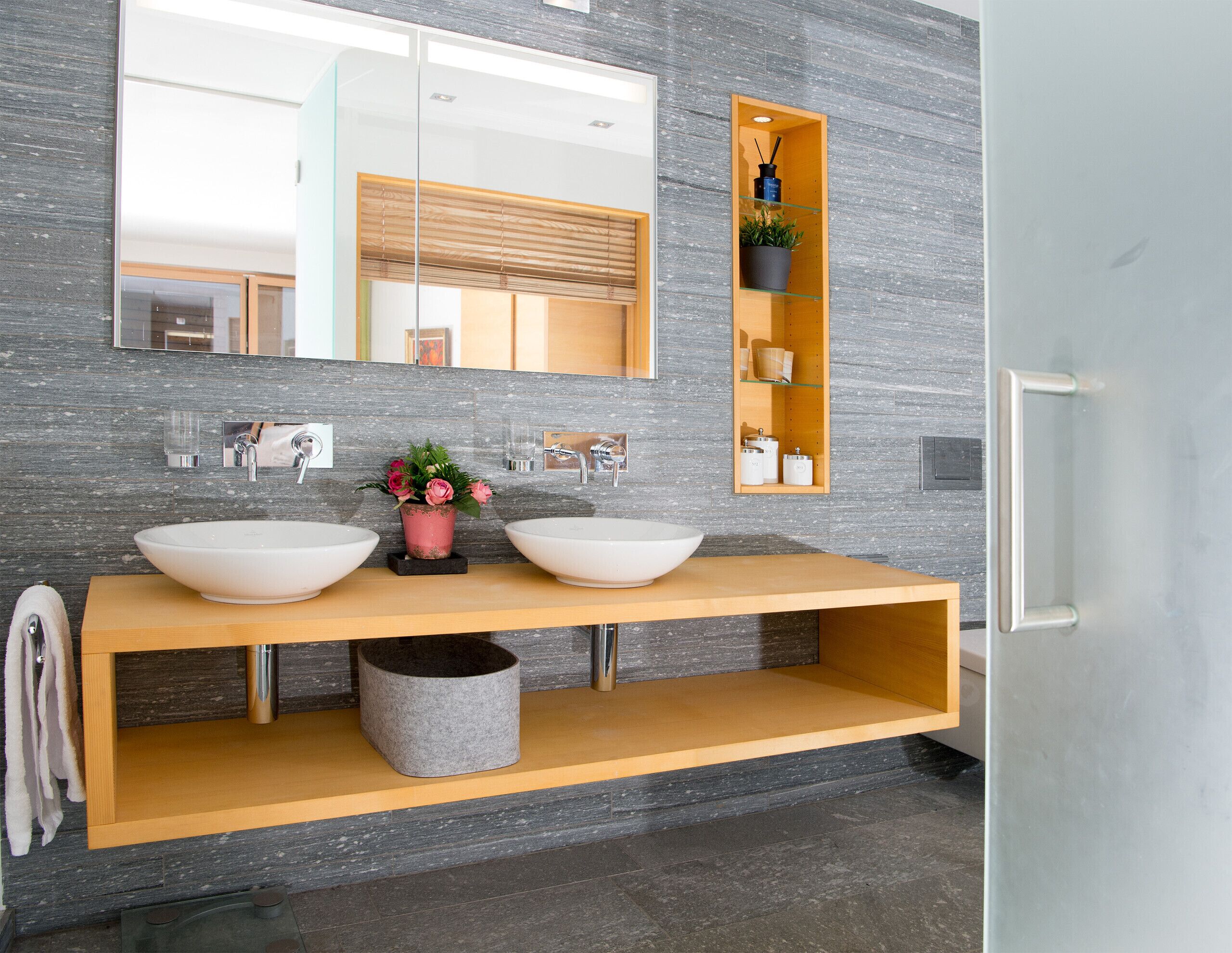 Une salle de bain moderne avec deux grands lavabos blancs, un miroir et un meuble-lavabo en bois.
