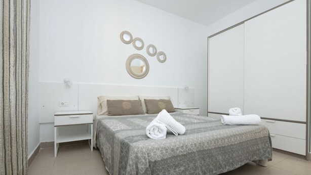 Une chambre à coucher moderne avec un grand lit, une table de chevet, une commode et une armoire.