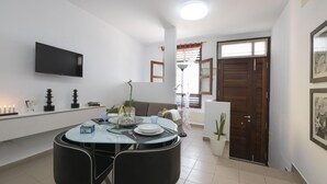 Un espace repas moderne avec une table ronde, des chaises noires et un téléviseur à écran plat fixé au mur.