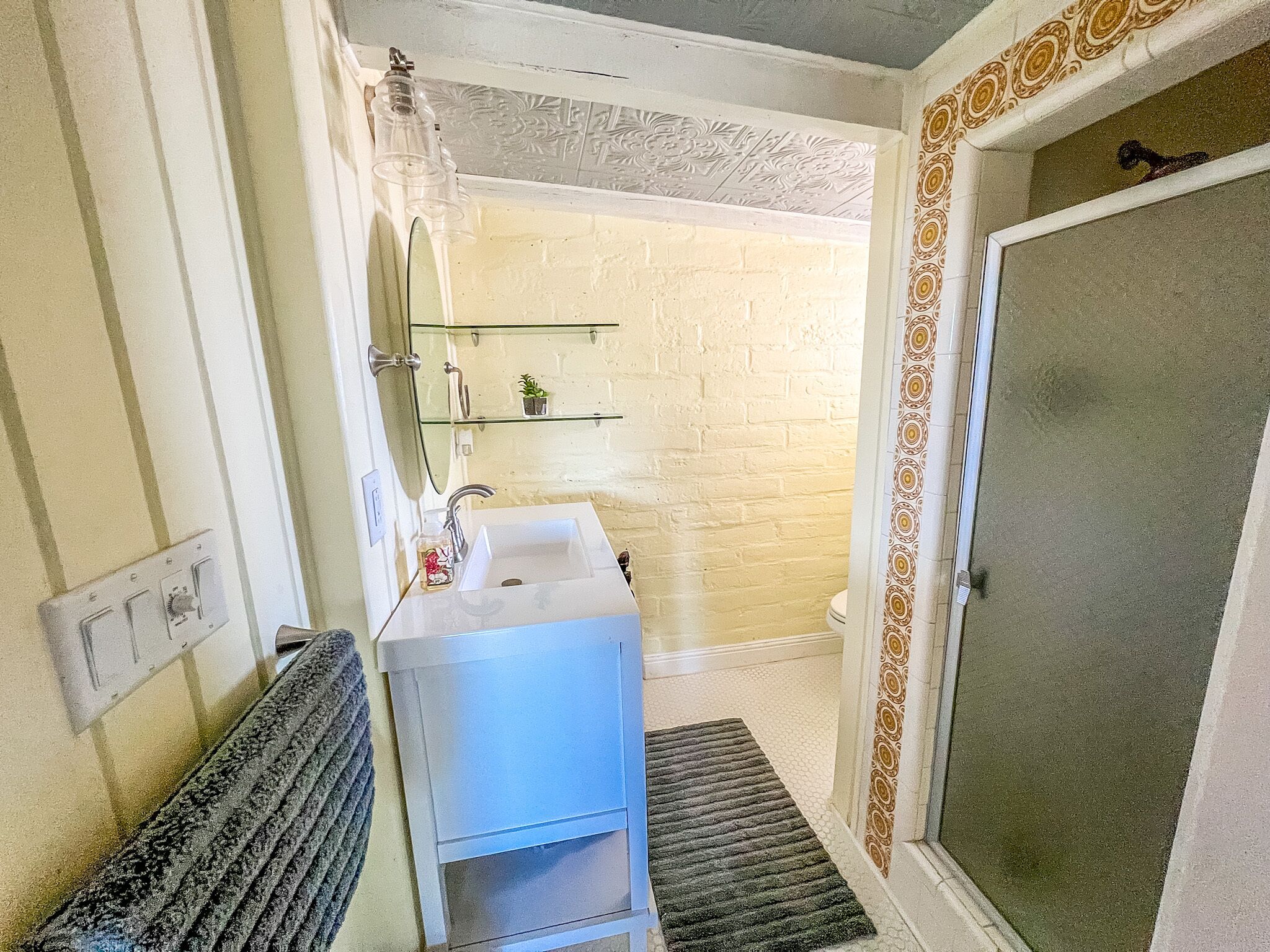 Ein Badezimmer mit einem weißen Waschbecken, einem Spiegel und einer Duschkabine.
