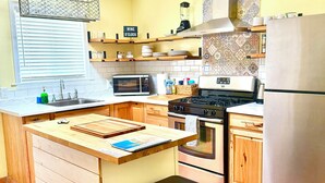 Une cuisine dotée d’un îlot central, d’une cuisinière, d’un four, d’un four à micro-ondes et d’un réfrigérateur.