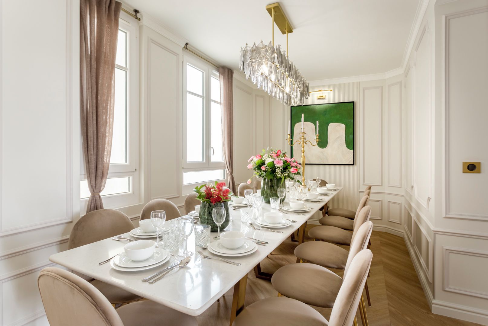 A formal dining room with a long table set for six, elegant chairs, a chandelier, and a large abstract painting on the wall.