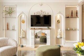 Una sala de estar con chimenea, televisor y estatuas decorativas.