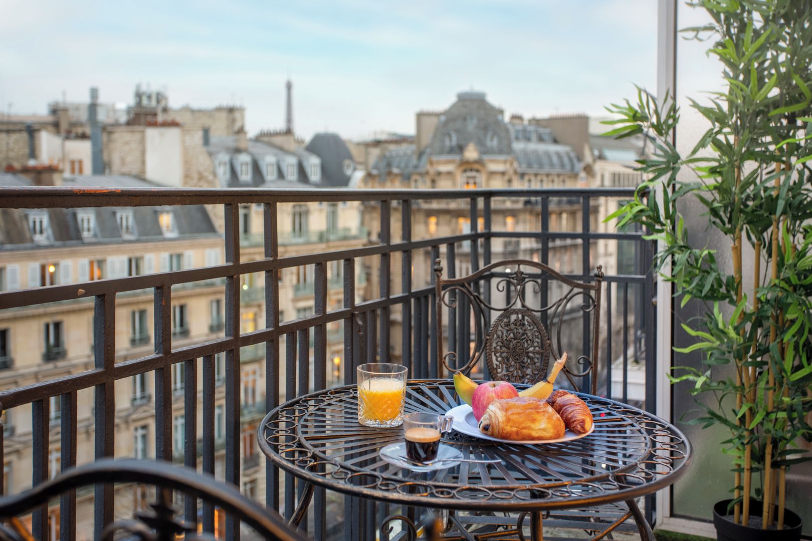 A balcony with a metal table, a chair, and a potted plant.