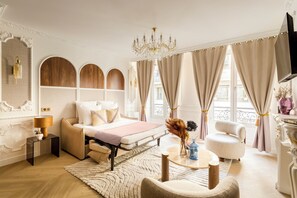 Quarto com cama, mesa de cabeceira, abajur, cadeira e um vaso decorativo.