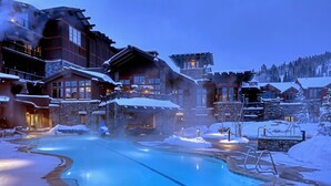 A heated outdoor pool surrounded by wooden buildings with stone accents, set in a snowy landscape. - New Ski-In/Out Ultra Luxe Deer Valley Condo in Intimate Lodge. Superb restaurant (Park City)