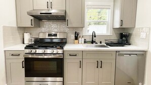 Una cocina moderna con electrodomésticos de acero inoxidable, armarios de tonos claros y un ventanal que proporciona luz natural.