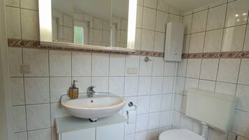 A bathroom with a white sink, a toilet, a mirror, and a hand dryer.