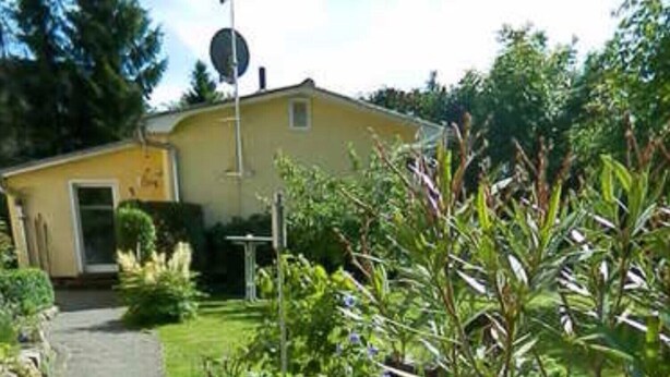 A pathway leading to a yellow building with a garden and a street sign.
