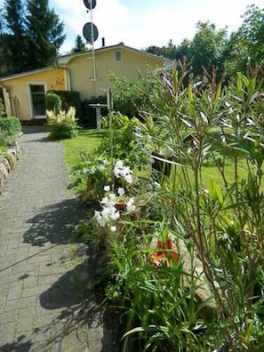 A pathway leading to a yellow building with a garden and a street sign.