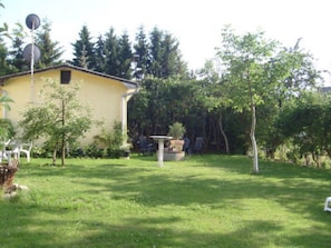 A yellow building with a satellite dish, surrounded by a grassy yard and trees.