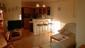 A living room with a TV, a sofa, and a dining area with chairs. - Apartment 'Heidtschmidhof Abendsonne' with Shared Terrace, Shared Garden and Wi-Fi (Wolgast)