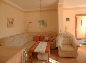 Un salon avec un canapé, un fauteuil, une table et une lampe.