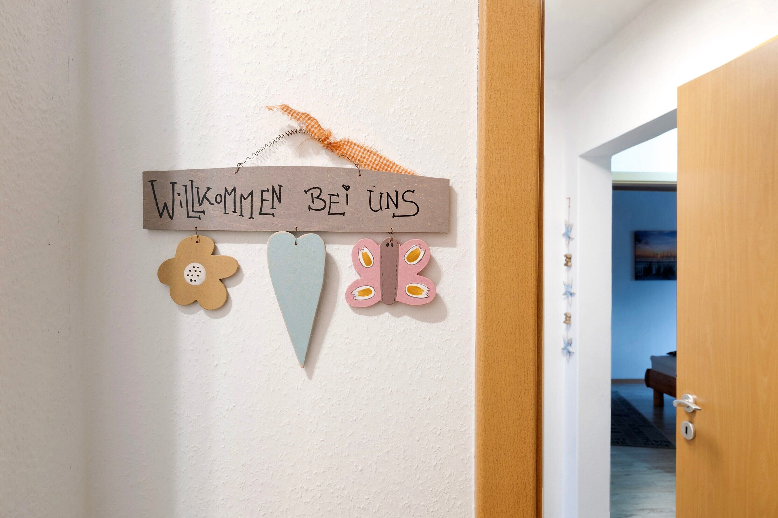 Un mur orné d’une pancarte de bienvenue, d’une décoration florale et d’un papillon.