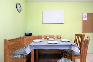 A dining area with a table set for four, a clock, and a whiteboard on the wall. - Apartment 'Wuddisferienwohnug' with Shared Terrace, Private Garden and Wi-Fi (Nordleda)