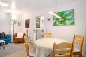 Une pièce comprenant une table à manger, des chaises, un canapé, un lampadaire et des œuvres d’art accrochées aux murs.