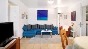 A living room with a TV, sofa, coffee table, and artwork on the walls. - Apartment 'Haus Loser' with Private Terrace, Shared Garden and Wi-Fi (Wasserburg (Bodensee))