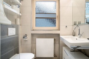 Une salle de bain comprenant des toilettes, un lavabo, un porte-serviettes et une fenêtre en verre dépoli.