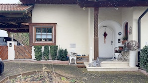 A house with a covered porch, a satellite dish, a wooden gate, a small garden, and a decorative star. - Apartment 'Haus Loser' with Private Terrace, Shared Garden and Wi-Fi (Wasserburg (Bodensee))