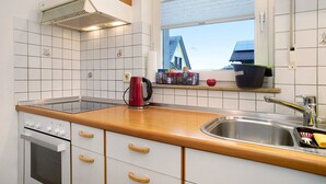 A kitchen with white cabinets, a wooden countertop, a stainless steel sink, and a window with a view of a house. - Apartment 'Haus Loser' with Private Terrace, Shared Garden and Wi-Fi (Wasserburg (Bodensee))