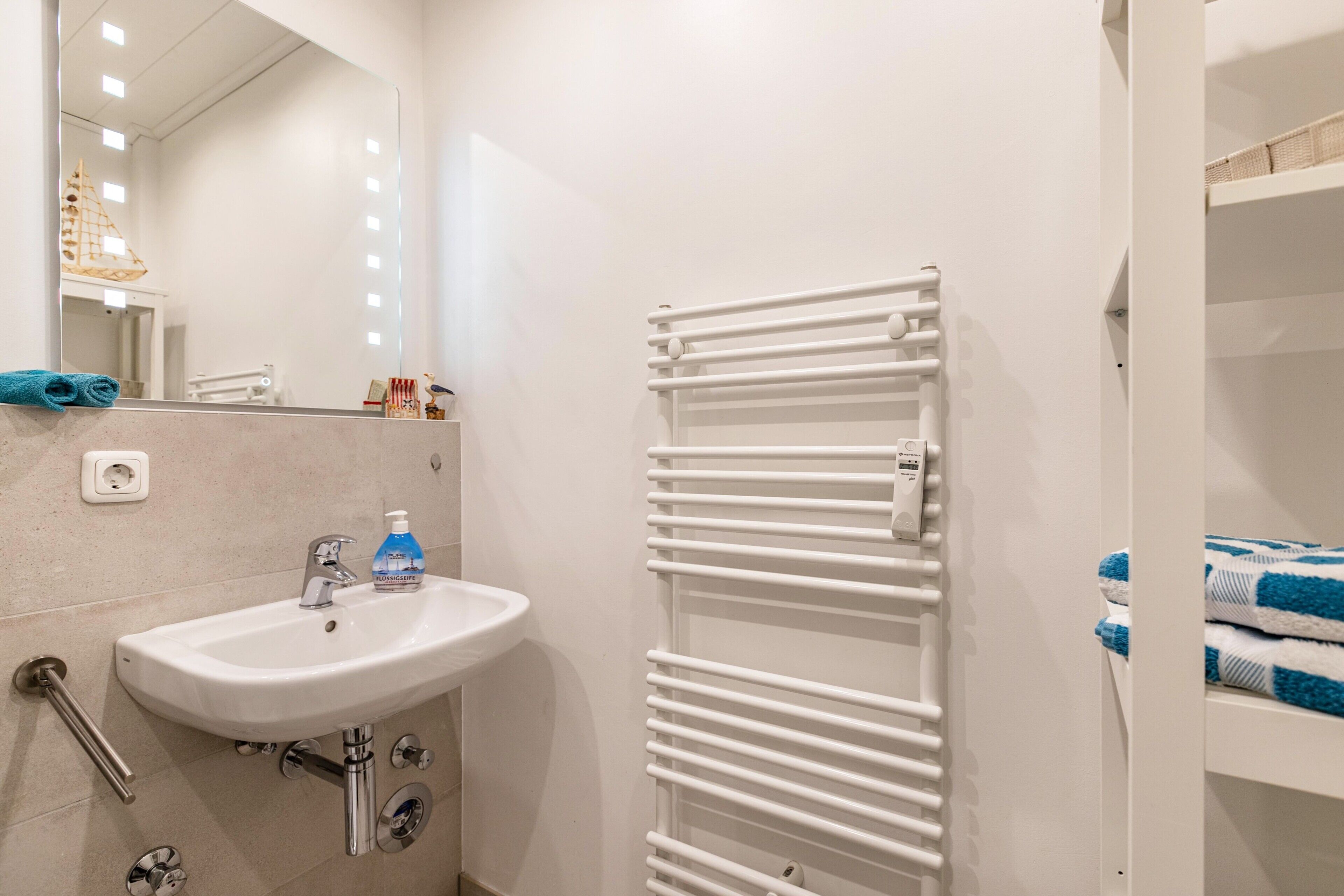 A bathroom with a white sink, mirror, and towel rack.