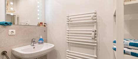 A bathroom with a white sink, mirror, and towel rack.