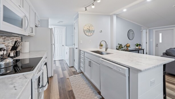 A modern kitchen with white cabinetry, a marble island, and a built-in dishwasher. - Completely remodeled 3BR/2BA,PET friendly,5min from Hurlburt Field,fully fenced  (Mary Esther)