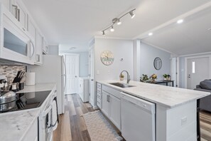 A modern kitchen with white cabinetry, a marble island, and a built-in dishwasher. - Completely remodeled 3BR/2BA,PET friendly,5min from Hurlburt Field,fully fenced (Mary Esther)