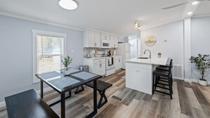 A modern kitchen with white cabinets, a central island, and a dining area with a table and bench. - Completely remodeled 3BR/2BA,PET friendly,5min from Hurlburt Field,fully fenced  (Mary Esther)