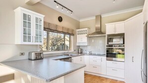 A modern kitchen with white cabinetry, a granite countertop, and a built-in stove.