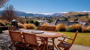 A wooden table and chairs set outdoors with a view of snow-capped mountains in the background.
