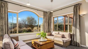 A room with a sofa, a coffee table, and large windows offering a view of the outdoors.